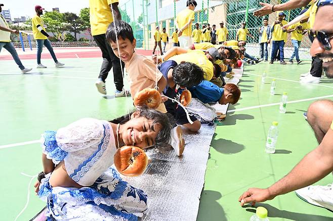 [울산=뉴시스] HD현대미포가 지난 28일 울산 동구 상진초등학교에서 '스리랑카 근로자 문화축제'를 개최한 가운데 스리랑카 어린이들이 손 안대고 빵먹기 이벤트에 참여하고 있다. (사진=HD현대미포 제공) photo@newsis.com *재판매 및 DB 금지