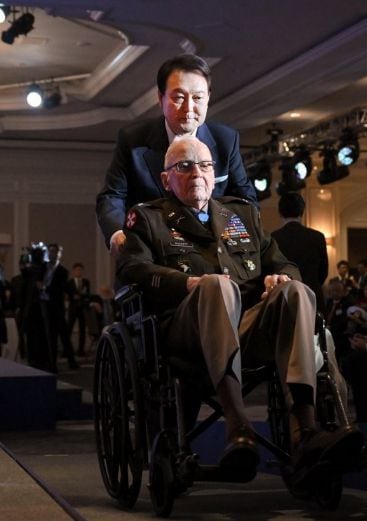 윤석열 대통령이 작년 4월 25일 미국 워싱턴DC 한 호텔에서 열린 한미동맹 70주년 기념 오찬에서 랠프 퍼켓 주니어 예비역 육군 대령의 휠체어를 밀어주고 있는 모습. /뉴시스