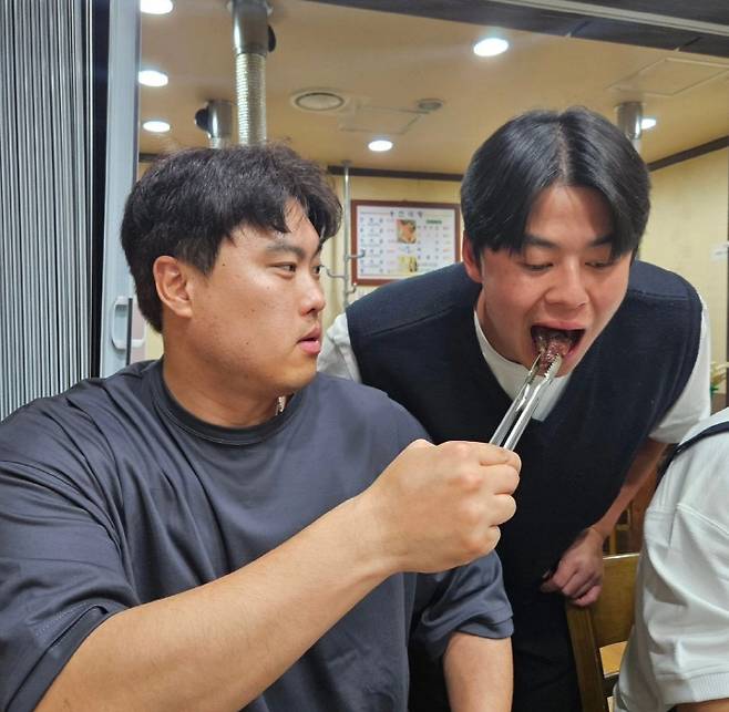 노시환에게 고기를 먹여주고 있는 류현진(왼쪽). 사진=99코퍼레이션 SNS