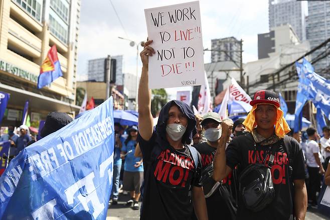 1일(현지시간) 필리핀 마닐라에서 열린 노동절 집회에 참석한 한 남성이  “우리는 죽기 위해서가 아니라 살기 위해 일한다”고 적힌 손팻말을 들고 있다. AP연합뉴스