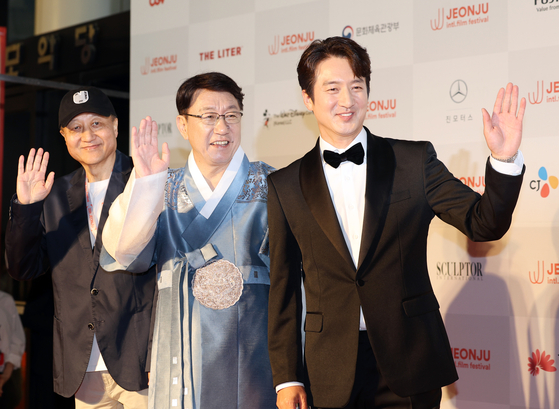 From left: Co-director Min Sung-wook, chairman Woo Beom-ki and co-director Jung Jun-ho pose for cameras on the red carpet before the opening ceremony of the 25th Jeonju International Film Festival at Sori Arts Center in Jeonju on Wednesday. [YONHAP]