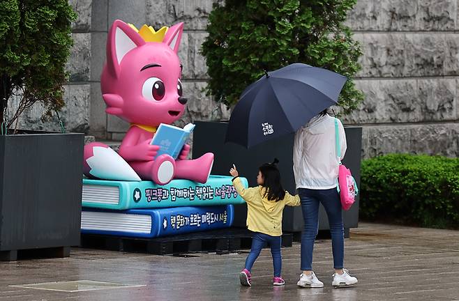 전국에 많은 비가 내렸던 지난해 5월 5일 어린이날 한 어린이가 서울광장에 설치된 핑크퐁 조형물 앞을 지나고 있다. [출처 : 연합뉴스]