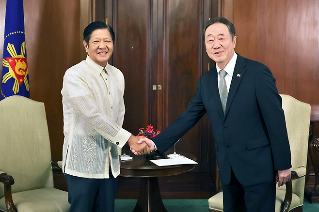 Philippine President Ferdinand Marcos Jr. (right) gives a tour to Maekyung Media Group Chairman Chang Dae-whan of the Malacañang Presidential Palace in Manila. The book in Mr. Marcos Jr.‘s left hand is an album with photographs of their late fathers taken together. [Photo by Han Joo-hyung]