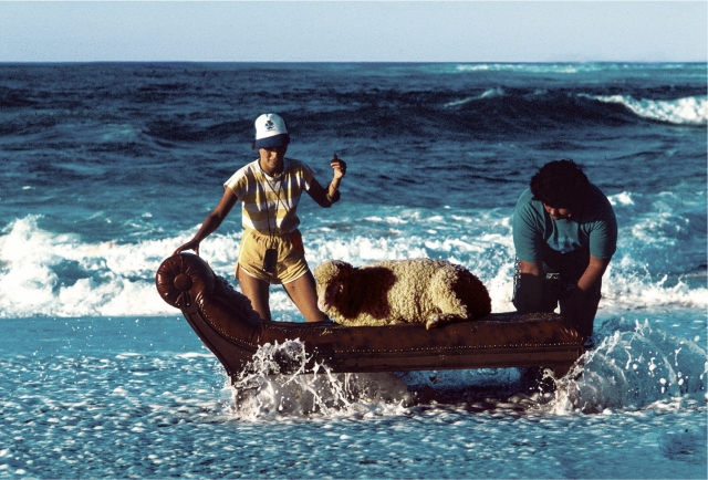 '힙노시스: LP 커버의 전설' 스틸사진. 록밴드 10cc의 '룩 히어' 앨범 커버 사진을 찍기 위해 하와이에서 바다에 설치한 소파에 양을 데려다 놓은 스태프들의 모습. 티캐스트 제공