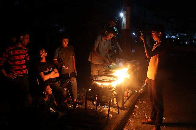 팔레스타인인들이 가자지구 남부 라파의 노점상 옆에 서 있다. [AFP]