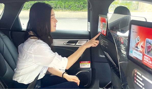 한국경제신문 기자가 중국 우한 도심에서 로보택시에 탑승해 출발 전 사용법을 살펴보고 있다.