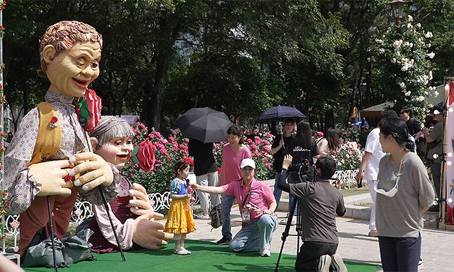 지난해 ‘장미꽃 필(feel) 무렵’ 행사장에서 한 어린이가 거리 퍼레이드용 인형 앞에서 기념 촬영을 하고 있다.