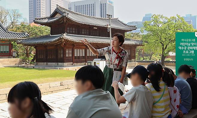 지난 4일 하나금융그룹의 ‘문화체험 프로그램’에 참여한 아동들이 덕수궁에서 역사 해설가의 설명을 들으며 문화재를 관람하고 있다. 하나금융그룹 제공