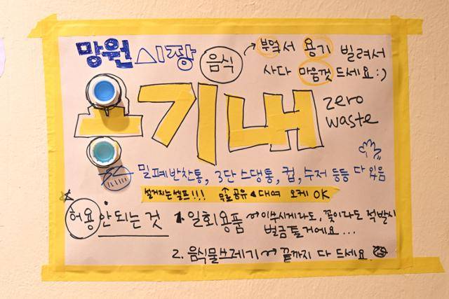 식판 데이가 열린 지난달 18일 망원시장 인근의 수리상점 곰손 벽에 게시된 '용기내 챌린지' 안내문. 이날 행사에서는 엄격하게 금지된 두 가지가 있었는데, 일회용품 사용과 잔반 남기기입니다. 제로웨이스트숍 알맹상점의 캠페이너(알짜) 나연씨는 "정말로 음식 남기면 1만 원 벌금으로 받습니다!"라고 당부했습니다. 박시몬 기자