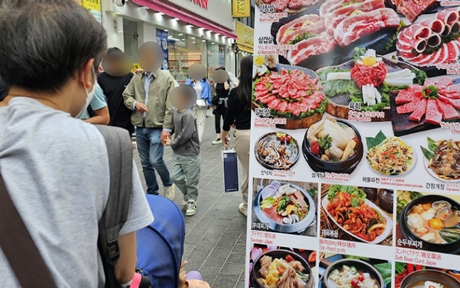 서울 중구 명동거리에 설치된 음식점 메뉴 입간판 사이로 시민들이 지나고 있는 모습. 사진=김경호 기자