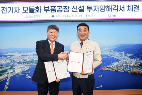 Hyundai Mobis CEO Lee Gyu-suk, left, shakes hands with Ulsan Mayor Kim Doo-kyum after signing an agreement to invest $66 million to build an EV module plant in the city on Thursday. [HYUNDAI MOBIS]