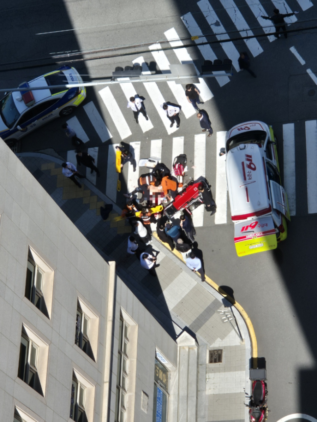 9일 오전 부산 연제구 부산법원 종합청사 길건너 맞은편 보도에서 피습을 당한 50대 남자가 구급 치료를 받고 있다. [독자 제공]