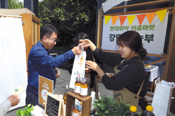 현대위아 소속 직원(왼쪽)이 ‘이음마켓’에서 지역 농가에서 만든 제품을 사고 있다. [현대위아 제공]