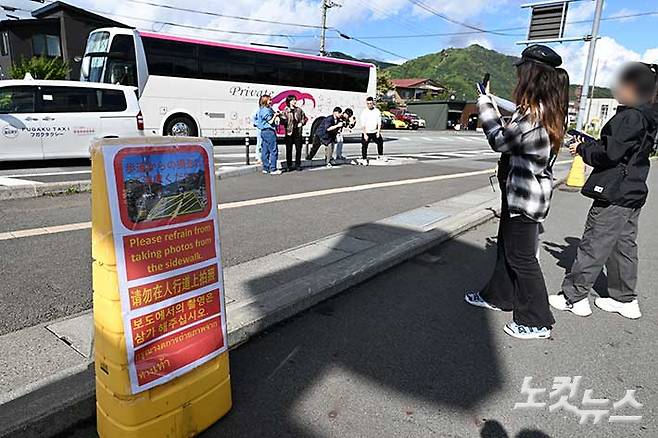 후지 가와구치코 로손 마치야쿠바마에점 앞 도로 경계 부근에 설치된 안내판 주변에서 관광객들이 인증샷을 촬영하고 있다. 최원철 기자