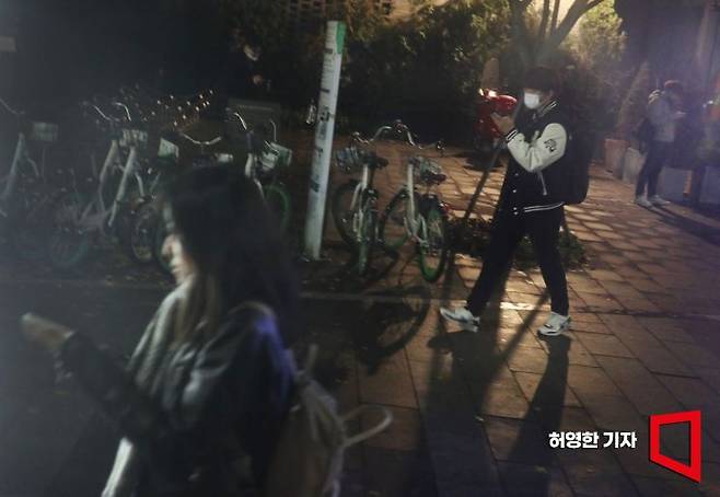 청년들이 퇴근길 어두운 길을 걸어가면서도 핸드폰에서 눈을 떼지 못하고 있다. 사진=허영한 기자