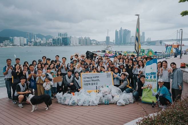 KB국민은행 임직원과 고객들이 13일 부산 광안리 해변에서 플로깅(쓰레기 줍기+조깅) 행사를 실시한 후 기념 촬영을 하고 있다. 사진=국민은행 제공