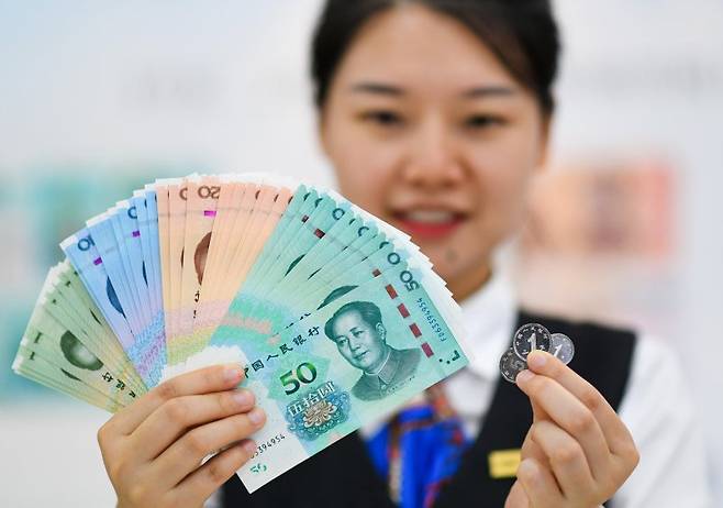 중국인민은행의 행원이 13일 새로 발행된 신권 지폐를 들어보이고 있다. 신화통신 뉴시스