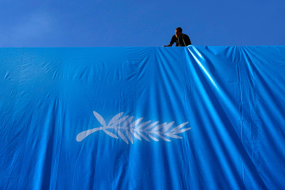 FILE PHOTO: Workers set up a giant canvas of the official poster which pays tribute to Japanese master filmmaker Akira Kurosawa and his late career feature Rhapsody in August, on the facade of the festival palace ahead of the opening ceremony of the 77th Cannes Film Festival in Cannes, France, May 12, 2024. REUTERS/Clodagh Kilcoyne/File Photo  〈저작권자(c) 연합뉴스, 무단 전재-재배포, AI 학습 및 활용 금지〉