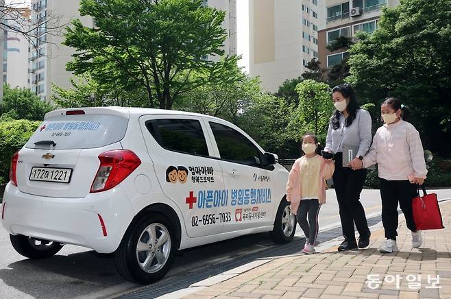 서울시는 맞벌이 가정 등에서 아이가 아플 때 전문 간호인력이 병원에 동행해주는 ‘아픈 아이 병원동행 서비스’로 호응을 얻고 있다.
 지난달 26일 서울 성북구의 한 아파트 앞에서 간호조무사 오지은 씨(47·가운데)가 초등학교 2·4학년 자매의 손을 잡고 동행 
차량으로 향하고 있다. 양회성 기자 yohan@donga.com