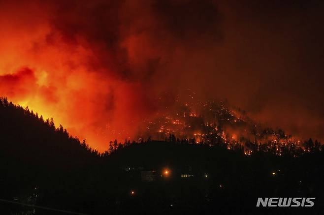 [웨스트켈로나=AP/뉴시스] 캐나다 서부에서 발생한 산불이 번지고 있는 가운데 산불 연기가 국경을 넘어 미국 북부까지 번졌다고 13일(현지시각) AP통신이 보도했다. 사진은 지난해 8월 18일 촬영한 캐나다 브리티시컬럼비아주 웨스트 켈로나의 한 주택 위 산허리에서 타오르는 산불. 2024.05.14.