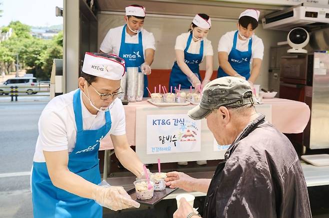방경만 KT&G 사장(왼쪽)이 지난 14일 서울역 인근 시립 무료급식소인 '따스한채움터'에서 간식으로 준비한 팥빙수를 전달하고 있다. KT&G 제공