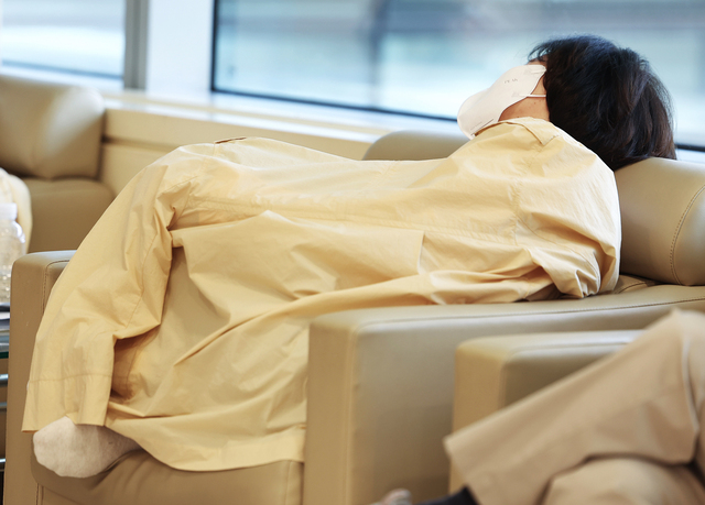 한 병원 내원객이 14일 서울시내 한 대형병원에서 외투를 담요처럼 덮고 소파에 기대 휴식을 취하고 있다. 연합뉴스