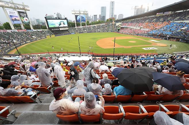 15일 오후 서울 송파구 잠실야구장에서 열린 2024 프로야구 키움 히어로즈와 LG 트윈스의 경기. 경기를 앞두고 시민들이 우산을 쓰고 비를 피하고 있다. [연합]