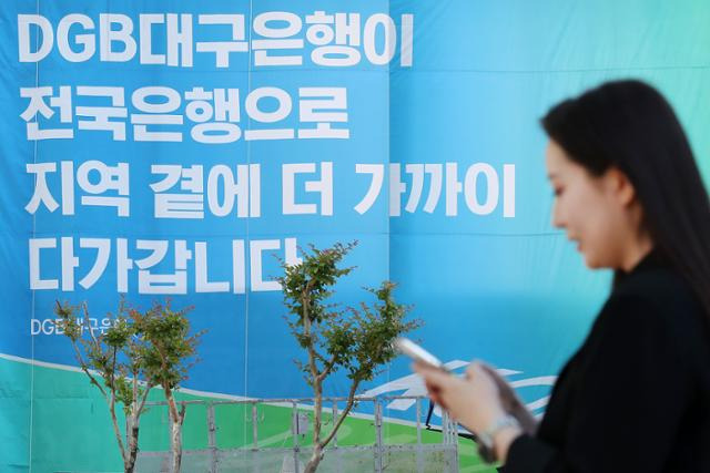 16일 오후 대구 수성구 대구은행 본점 앞 열린광장에서 은행 직원이 대구은행의 시중은행 전환 인가를 축하하는 현수막 앞을 지나고 있다. 뉴스1