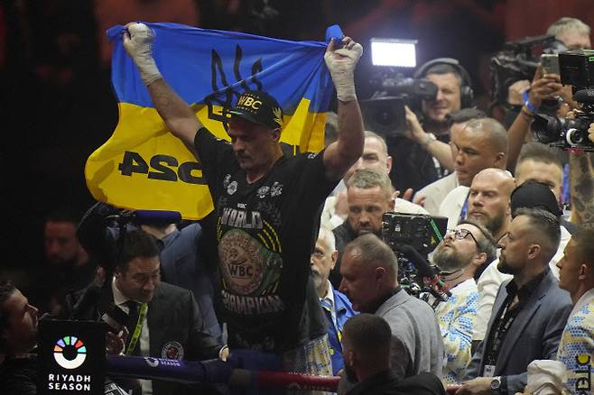 우크라이나 헤비급 복서 올렉산드르 우식이 타이슨 퓨리를 꺾고 세계 통합챔피언에 오른 뒤 우크라이나 국기를 들고 기뻐하고 있다. 사진=AP PHOTO