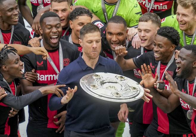 레버쿠젠의 사비 알론소 감독(가운데)이 19일 아우크스부르크에 2-1로 이기고 무패 우승을 확정한 뒤 선수들과 함께 챔피언 트로피를 들어보이고 있다. 레버쿠젠 | AP연합뉴스