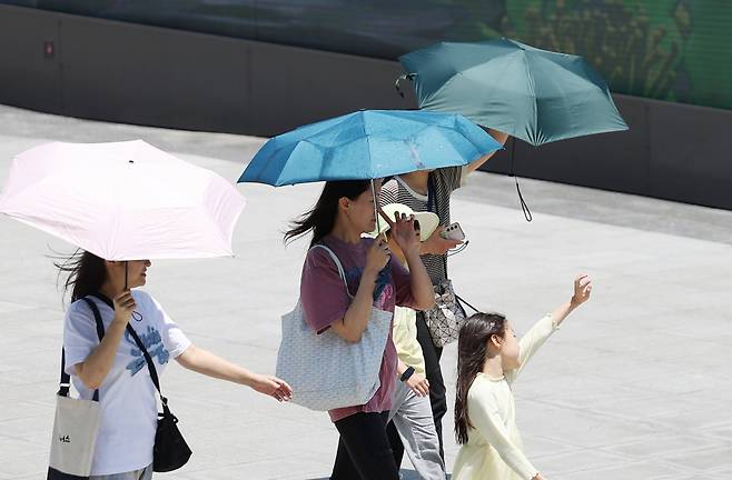 19일 서울 낮 최고기온이 28도까지 오르면서 서울 종로구 세종대로 사거리를 걷는 시민들이 양산을 쓰고 있다./사진=뉴스1