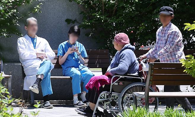 지난 16일 서울 시내의 대형병원에서 휴식을 취하는 의료진 앞으로 환자 가족이 이동하고 있다. 뉴스1