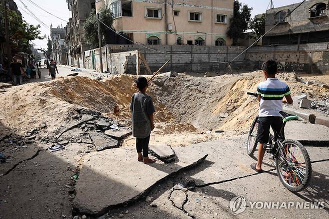 이스라엘군의 폭격으로 라파 시내에 패인 구덩이 (라파 AFP=연합뉴스) 18일(현지시간) 팔레스타인 가자지구 최남단도시 라파에서 어린이들이 이스라엘군의 폭격으로 거리에 패인 구덩이를 살펴보고 있다. 2024.5.18