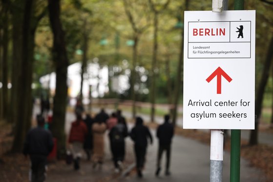 지난해 10월 독일 베를린의 한 망명 신청자 등록 센터로 가는 길을 안내하는 표지판. 그 뒤로 행인들이 걸어가고 있다. EPA=연합뉴스