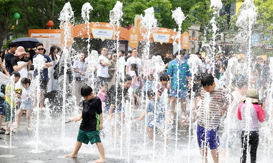 Kids splash around in the water at a fountain in Gwanghwamun Square in central Seoul on May 4, as the midday temperature in Seoul rose to an early summer-like weather. [NEWS1]