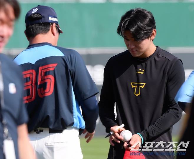 '이렇게 황송할 때가...' 정성스럽게 사인을 한 김도영이 공손하게 공을 건네고 있다.