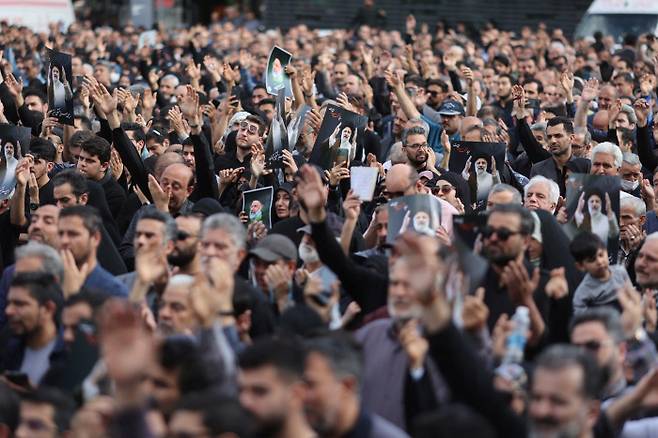 광장에 모인 시민들 ‘추모의 손짓’ 이란 수도 테헤란 시민들이 20일(현지시간) 시내 발리아스르 광장에서 헬기 추락 사고로 숨진 에브라힘 라이시 대통령의 사진을 들고 그를 추모하고 있다. 로이터연합뉴스
