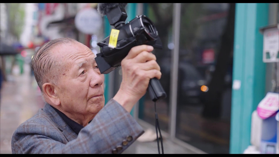 Former Busan International Film Festival director Kim Dong-ho films with his camcorder in a scene from documentary film "Walking in the Movies," directed by Kim Lyang. [SCREEN CAPTURE]