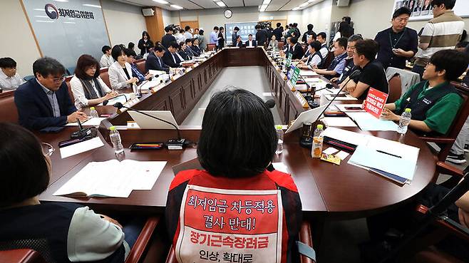 최저임금위원회에서 '최저임금 차등 적용 결사반대'라고 적힌 조끼를 입고 있는 전지현 전국돌봄서비스노조 위원장