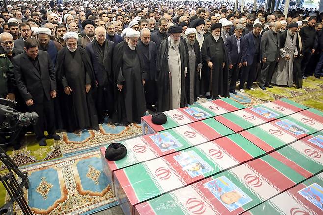 이란 최고지도자 아야톨라 알리 하메네(가운데)와 이란 성직자 및 관리들이 에브라힘 라이시 이란 대통령과 호세인 아미르 압돌라안 외무장관을 포함한 헬리콥터 사고 희생자의 장례식이 테헤란에서 열린 22일(현지 시각) 기도하고 있다. / AFP 연합뉴스