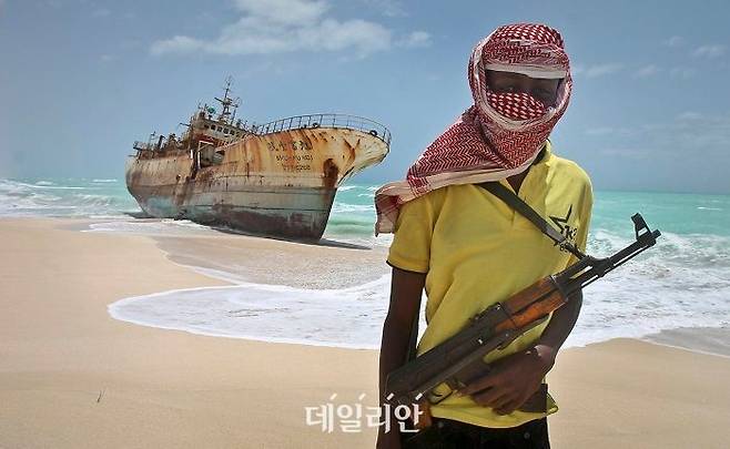 2012년 대만의 어선을 납치해 석방금을 받아낸 소말리아 해적 한 명이 소말리아 호비요 부근에서 배 옆에 서 있다. ⓒ뉴시스