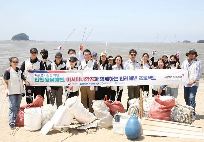 아시아나항공 직원들이 23일 인천 영종도 '용유해변'에서 반려해변 정화 활동을 펼치고 기념촬영을 하고 있다. 아시아나항공 제공