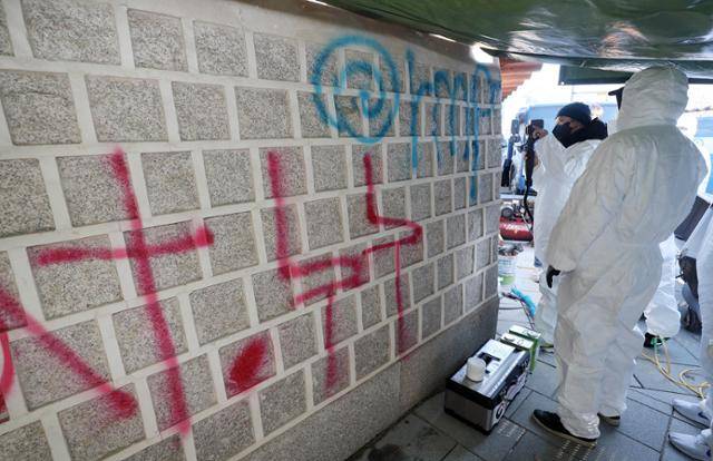 지난해 12월 문화유산 복원 전문가들이 서울 종로구 국립고궁박물관 쪽문 경복궁 담벼락에 '1차 테러범'이 스프레이로 쓴 낙서를 지우고 있다. 연합뉴스