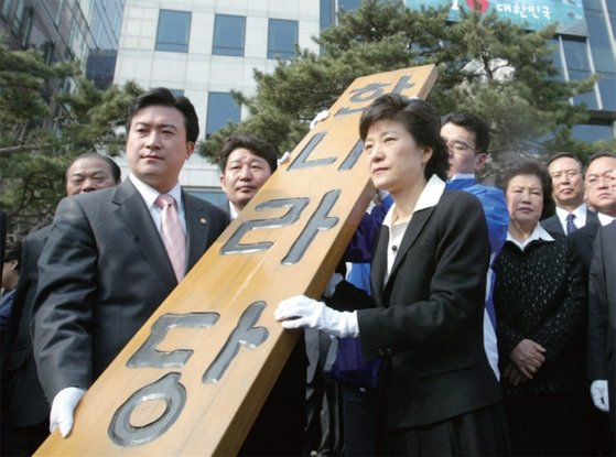2004년 3월 노무현 당시 대통령에 대한 탄핵 역풍으로 침몰 직전이던 한나라당의 새로운 대표로 선출된 박근혜 의원이 첫 출근날 당사 현판을 들고 천막당사로 향하고 있다.