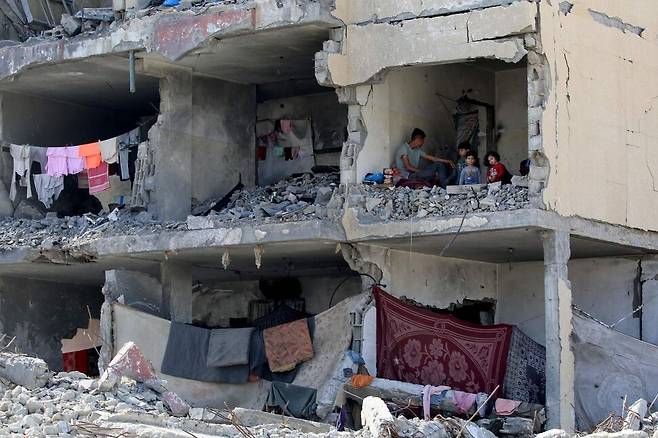 5월22일 이스라엘군의 공격으로 벽이 통째로 날아간 건물 안에서 한 남성이 아이들과 함께 앉아 있다. AFP 연합뉴스