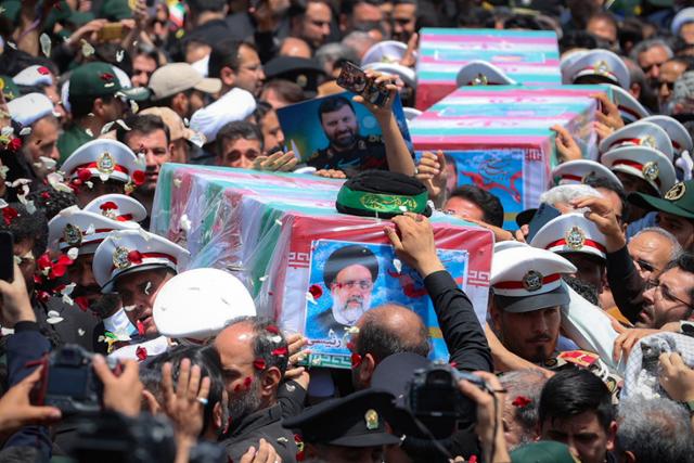 23일 이슬람 시아파 성지인 이란 호라산주 마슈하드에서 에브라힘 라이시 대통령과 헬기 추락 희생자들의 관이 운구되고 있다. 마슈하드=AP 뉴시스