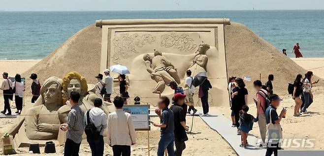 [부산=뉴시스] 하경민 기자 = '2024 해운대 모래축제' 개막일인 24일 부산 해운대해수욕장에서 시민과 관광객들이 다양한 모래조각 작품을 둘러보고 있다. 27일까지 열리는 이번 축제는 '세계 미술관 여행'을 주제로 세계적인 모래작가 12명이 만든 총 20개 작품을 전시하며, 이들 모래작품은 축제가 끝난 이후에도 6월9일까지 그대로 전시될 예정이다. 2024.05.24. yulnetphoto@newsis.com