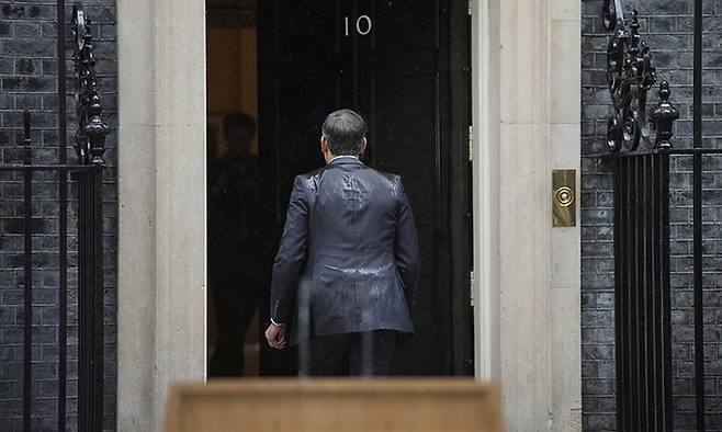 리시 수낵 영국 총리가 22일(현지시각) 런던 총리 관저 밖에서 내리는 비를 맞으며 총선 일정을 발표한 후 관저로 들어가고 있다. AP뉴시스