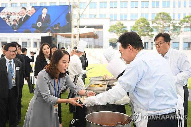 ‘대통령의 저녁 초대’, 앞치마 입은 윤석열 대통령 (서울=연합뉴스) 홍해인 기자 = 윤석열 대통령이 24일 서울 용산 대통령실 청사 잔디마당에서 열린 '대통령의 저녁 초대' 출입기자단 초청 만찬 간담회에서 취재진에게 김치찌개를 배식하고 있다. 2024.5.24 [대통령실 제공. 재판매 및 DB 금지] hihong@yna.co.kr