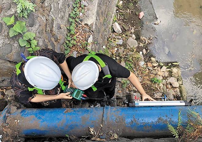 지난 20일 인도네시아 발리 덴파사르시에서 현지 관계자들이 초음파 유량계를 수도관에 붙여 물이 얼마나 새고 있는지 점검하고 있다. /한국수자원공사